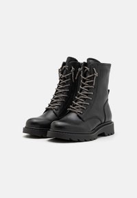 Bottines en cuir noir avec une surface texturée, dotées de lacets métalliques, d'une semelle rembourrée et d'une semelle extérieure robuste et rainurée.