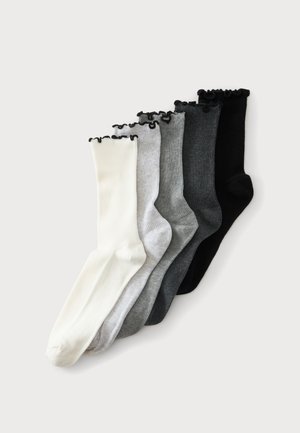 Cinq paires de chaussettes côtelées en blanc, gris clair, gris moyen, gris foncé et noir avec une bordure noire froncée en haut, disposées côte à côte.