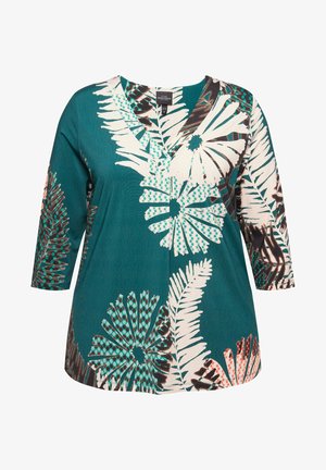 Taki tuniikka, jossa on V-pääntie, ja valkoisista ja tummansinisistä kukkakuviosta. Pitkät hihat, pehmeä kangas ja rento istuvuus.