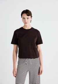 Brown cotton t-shirt with short sleeves and a crew neckline, paired with black and white striped trousers featuring a drawstring waist.