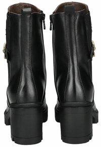 Bottines en cuir noir avec un talon épais, des zips latéraux et des accents de quincaillerie décoratifs sur les côtés extérieurs. Texture lisse.