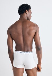 Boxer shorts bianchi in cotone con una cintura elastica con logo, visti da dietro, che mostrano un design aderente e liscio.