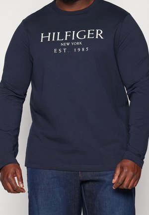 Navy long-sleeve T-shirt made of cotton, featuring a crew neck and white "HILFIGER NEW YORK EST. 1985" text on the front. Smooth texture.