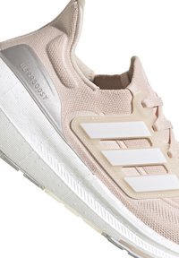 Scarpa sportiva rosa chiaro con tomaia in maglia, logo Three Stripes bianco, controfianco testurizzato e una suola intermedia spessa bianca con suola esterna a motivi.