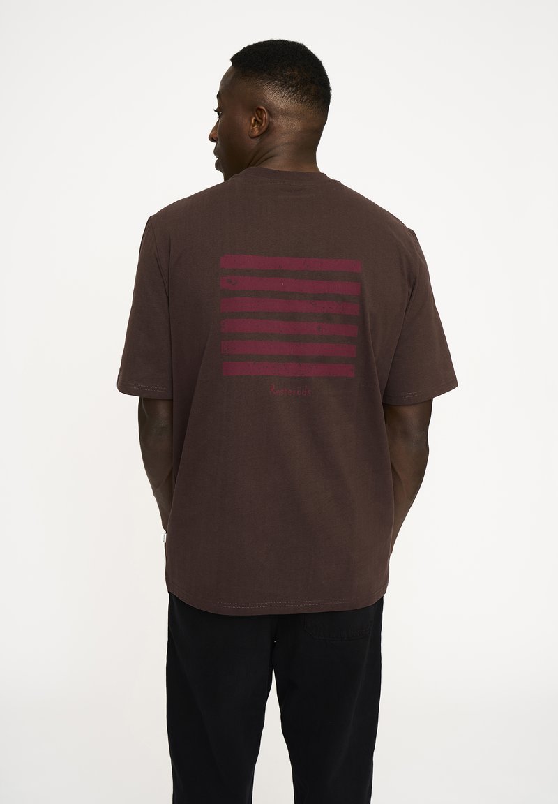 Brun bomulds t-shirt med korte ærmer, med et mørkerødt stribet grafisk mønster på ryggen og en rund hals.