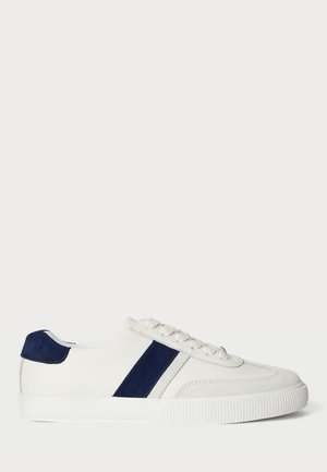 Białe sneakersy z granatowymi akcentami, teksturowanym zamszowym paskiem i płaskimi sznurowadłami. Posiadają gumową podeszwę z teksturowanym wzorem. Klasyczny design.