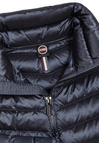 Marinblå vadderad jacka med hög krage, med dragkedja, mjuk textur och en Colmar-märkt etikett med flerfärgade accenter.