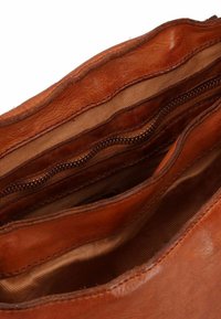 Interno di una borsa in pelle marrone con due scomparti, di cui uno con zip. Texture liscia, cuciture a punto, e rivestimento in tessuto beige.