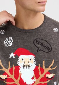 Grau gestrickter Pullover mit einem Weihnachtsmann-Design, das Geweihen, roten Akzenten, Schneeflocken und dem Text "YEAH!!!" in einer Sprechblase zeigt.
