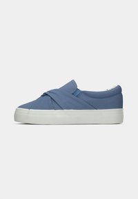 Ballerine en toile bleue avec un design torsadé à l'avant, semelle en caoutchouc blanche et parois latérales texturées. Accents en matériaux contrastants.