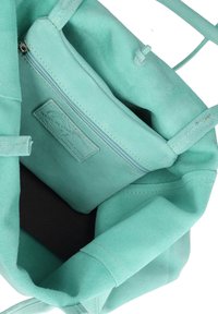Mintgroene neplederen handtas met één binnenzak met rits. De binnenkant heeft een zwart gestructureerde voering en eenvoudige stikdetails.