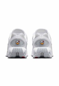Zapatillas deportivas blancas con parte superior de malla, suave cuello acolchado y amortiguación de aire visible. Suela de goma con un dibujo en la banda de rodadura y acento rojo.