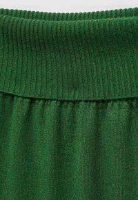 Tissu côtelé vert avec une large taille douce et une texture froncée en dessous, mettant en valeur une teinte riche et profonde ainsi qu'une finition lisse.