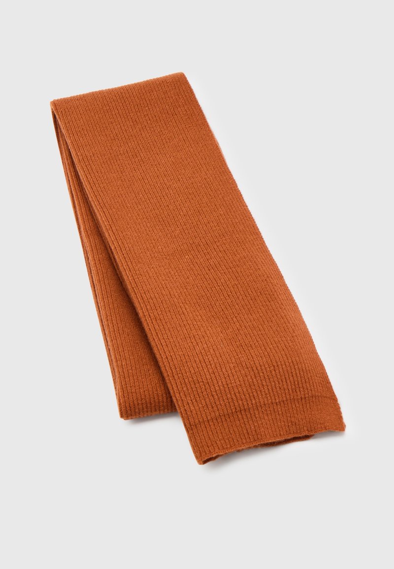 Écharpe en tricot côtelé orange pliée soigneusement sur un fond gris clair, mettant en valeur la texture et la couleur chaude d'automne.