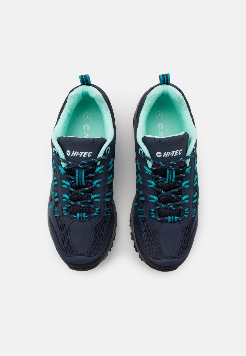 Zapatillas de senderismo azul marino con parte superior de malla y sintético, detalles en turquesa, suela de goma y cordones reflectantes. Asa en el talón.