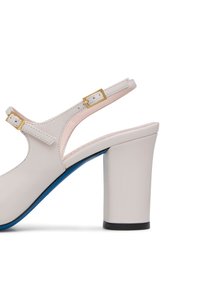 Sandalo con tacco in pelle bianca, con tacco a blocco spesso, cinturino regolabile e dettagli in oro. Presenta una suola blu e un interno rosa.