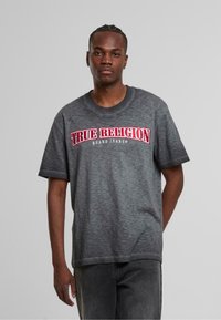 Šedé tričko s krátkým rukávem a kulat�ým výstřihem, na němž se nachází silné červené vyšití loga "TRUE RELIGION" přes hruď.