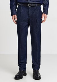 Pantaloni in denim blu scuro con vestibilità dritta, caratterizzati da pieghe frontali, tasche laterali e una cintura nera. Texture liscia e linee pulite.