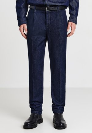 Dunkelblaue Jeans mit geradem Schnitt, ausgestattet mit vorderen Falten, seitlichen Taschen und einem schwarzen Gürtel. Glatte Textur und klare Linien.