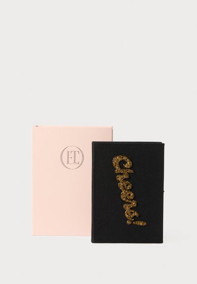 Cadernetas de tecido preto com o destaque cintilante em dourado "Cheers!", apresentadas numa caixa rosa suave com um logótipo circular.