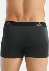 Svarta herrboxershorts gjorda av elastisk tyg, med en bred elastisk midjeband med grå detaljer och subtila strukturerade mönster på sidorna.