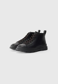 Black leather ankle boots with a textured finish, featuring brown laces, a thick rubber sole, and rear pull tab for easy wear.
