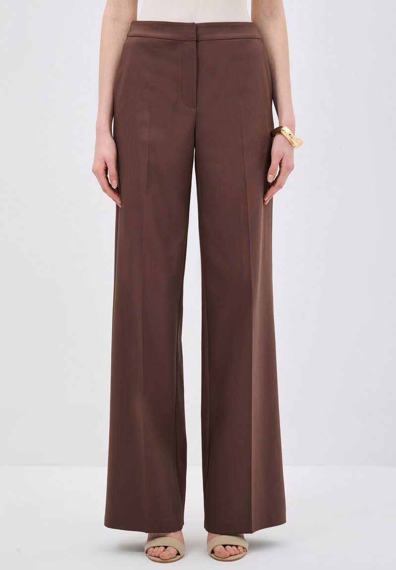Pantaloni larghi marroni con una texture liscia e una vita rifinita, caratterizzati da dettagli plissettati e una vestibilità dritta fino a terra.
