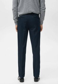 Granatowe spodnie w prążki o prostym kroju, wykonane z gładkiej tkaniny. Posiadają dwie tylne kieszenie i dyskretne szlufki na pasek.