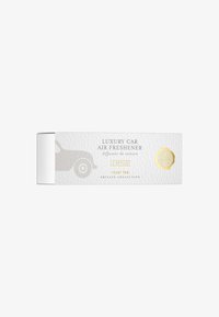 Packaging di un deodorante per auto di lusso in bianco con una finitura testurizzata. Presenta una silhouette di auto grigia, accenti dorati e l'etichetta del profumo "royal tea".
