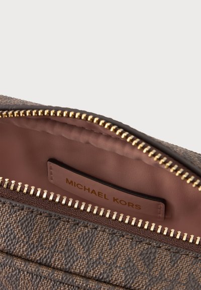 Καφέ υφασμάτινη τσάντα Michael Kors με μερικά ανοιχτό φερμουάρ που αποκαλύπτει ροζ υφασμάτινη εσωτερική επένδυση και ετικέτα με την μάρκα στο εσωτερικό.