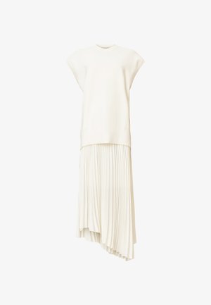 Lichtbeige twee-delig jurkje met een gladde top met korte mouwen en een geplooide asymmetrische rok. Gemaakt van ademende stof.