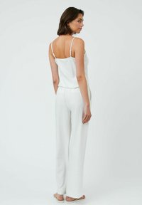 Completo bianco e leggero a due pezzi composto da un top camicia aderente con spalline sottili e pantaloni larghi e ampi con un delicato motivo di texture.