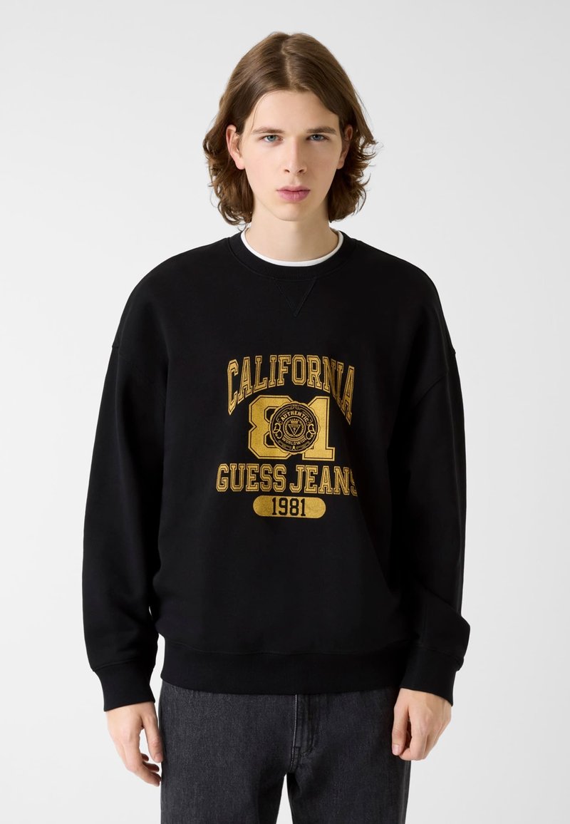 Μαύρο φούτερ με έντονο χρυσό γραφικό "CALIFORNIA GUESS JEANS 1981". Διαθέτει στρογγυλή λαιμόκοψη και ριμπ μανσέτες. Λεία υφή.