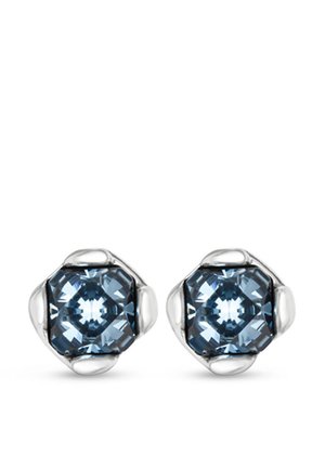 Pendientes en tono plateado con cristales azules en forma octagonal, montados en una base metálica lisa con bordes redondeados, que exhiben un diseño facetado.