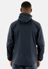 Veste coupe-vent bleu marine en matériau léger, dotée d'une capuche, de poignets élastiques et d'une texture lisse. Design minimaliste.