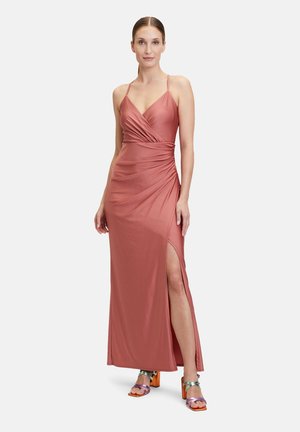 Robe maxi rose à buste drapé, avec des fines bretelles et une fente sur le côté. Le matériau semble lisse avec un léger éclat.