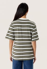 Camiseta de manga corta a rayas verde y blanca con cuello redondo. El material parece suave; presenta un corte recto y detalles de apertura lateral.