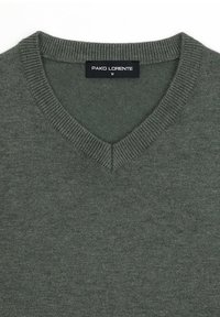 Sweter typu V-neck w ciemnozielonym kolorze, o dzianinowej teksturze, z prążkowanymi brzegami. Metka 'PAKO LORENTE', rozmiar M widoczna przy kołnierzyku.