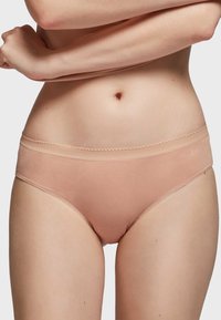 Beige katoenen bikini slip met een smalle, gegolfde tailleband en een gladde textuur. Heeft een minimalistisch ontwerp zonder patronen of versieringen.