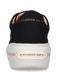 Sneaker nera con tomaia in tessuto morbido, suola bianca e dettagli dorati. "Alexander Smith" in lettere dorate sul retro.