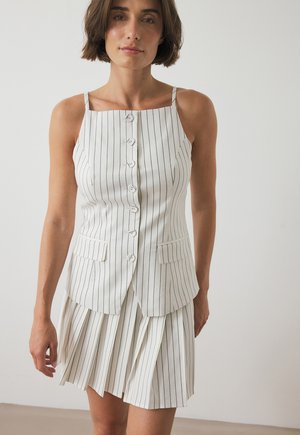 White sleeveless dress with vertical black stripes, button front, and double pockets; features a pleated skirt and fitted bodice design.