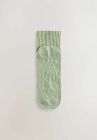 Világoszöld zokni bordázott mintával. Csúszásgátló szilikon pöttyök a talpon. Simább textúra, bokáig érő, lekerekített orr-résszel.