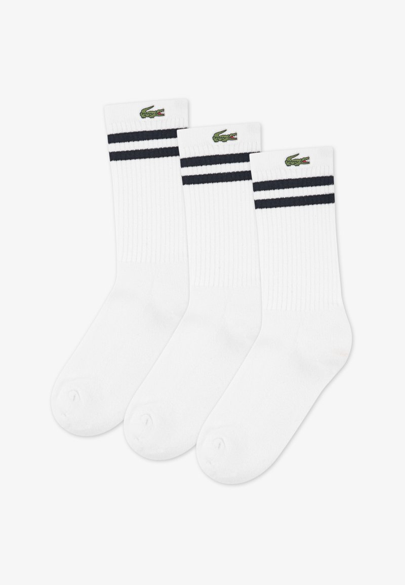 Calzini alla caviglia bianchi a coste con due strisce blu navy nella parte superiore e un logo di coccodrillo verde. Set di tre paia.
