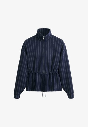 Temno modra jakna na zadrgo z belimi navpičnimi črtami, visokim ovratnikom, dolgimi rokavi in nastavljivim pasom z vrvico.