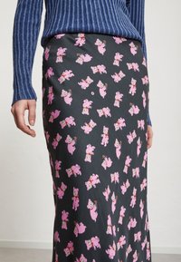 Černá sukně s hravým vzorem růžového medvídka, vyrobená z měkkého materiálu a ve tvaru A, doplněná živým modrým pleteným svetrem.