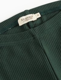 Close-up de um tecido côtelê verde escuro mostrando o rótulo da MarMar Copenhagen e a etiqueta de tamanho marcada como 5Y na parte interna da gola de uma peça de vestuário.