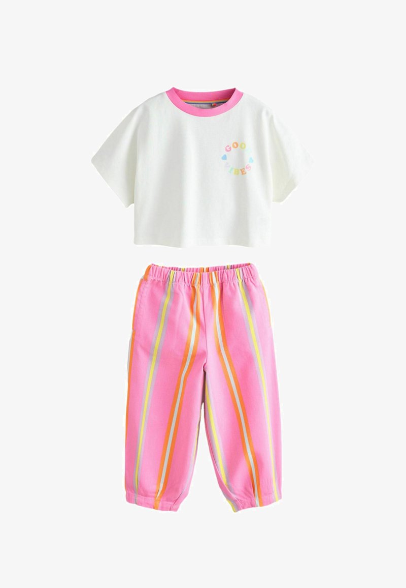 Biały krótki t-shirt z różowym kołnierzykiem i napisem „Good Vibes”; luźne różowe spodnie w pionowe pomarańczowe i żółte paski, z elastycznym pasem.