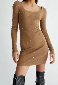 Strickkleid mit langen Ärmeln in Hellbraun, mit gerippter Textur, verziert mit kleinen silbernen Nieten, mit quadratischem Ausschnitt und figurbetontem Schnitt.