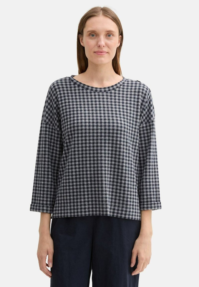 Top a scacchi bianchi e neri con scollatura rotonda, maniche lunghe e vestibilità rilassata. Tessuto morbido con una sottile texture.