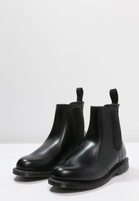 Czarne skórzane botki Chelsea z elastycznymi panelami bocznymi, zaokrąglonym noskiem i pętlami. Posiadają teksturowaną gumową podeszwę zapewniającą przyczepność.